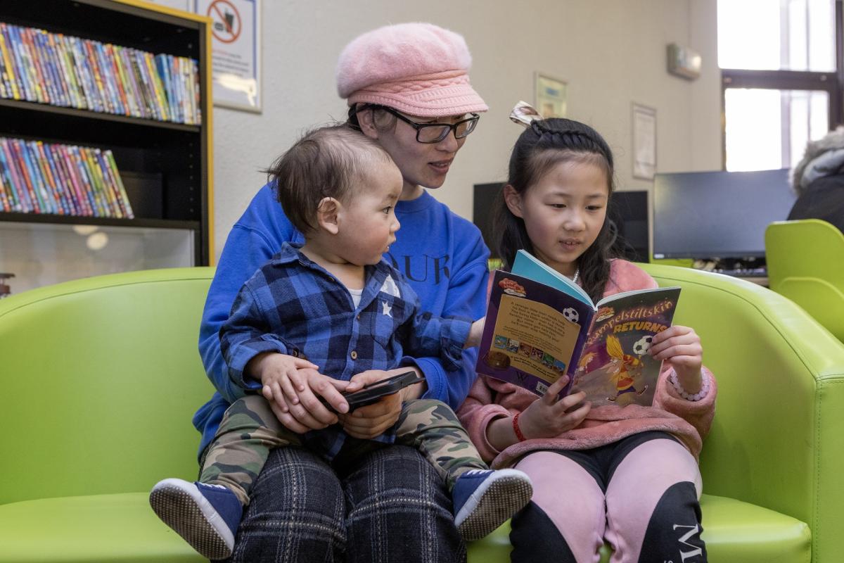 Woman reading with two children in a library