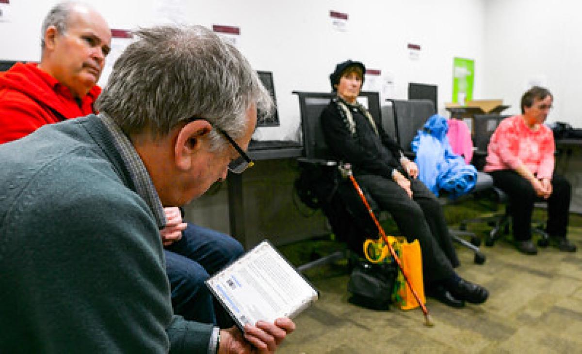 A group of older citizens sit and talk on chairs in a library.