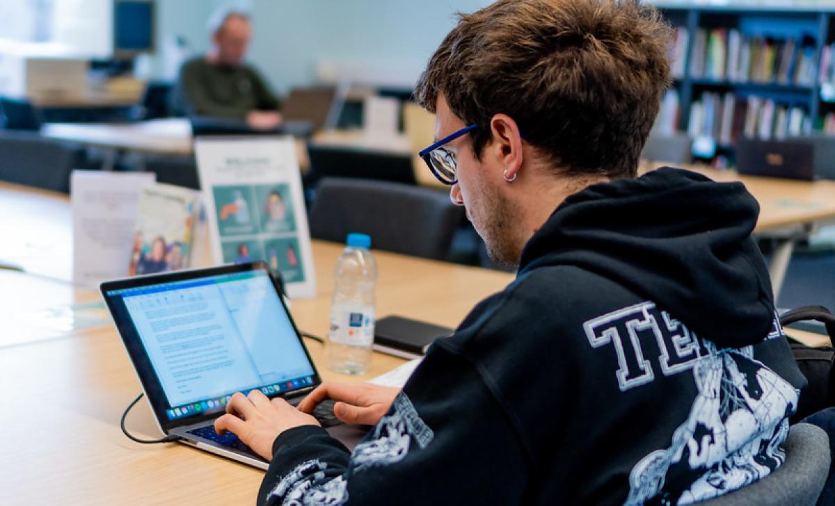 A man wearing glasses sits working at a laptop.