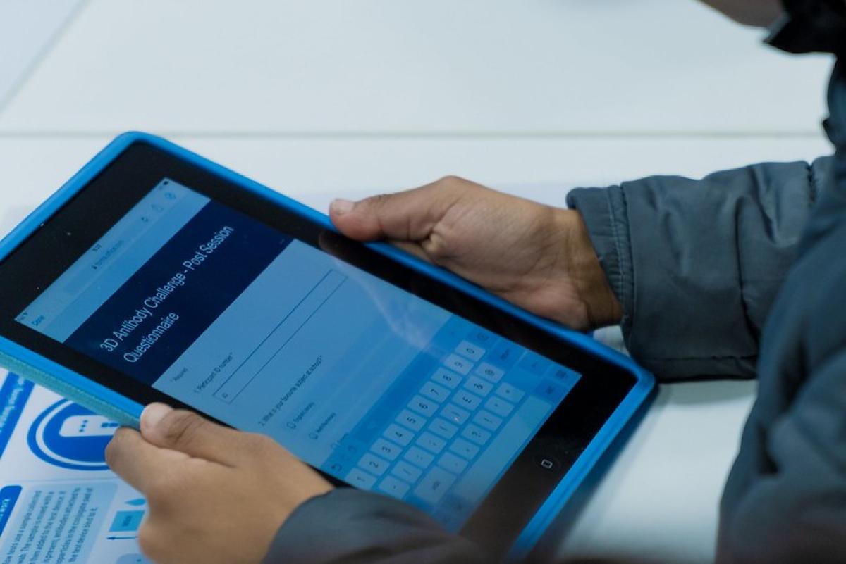 A hand holds a tablet displaying a keypad.