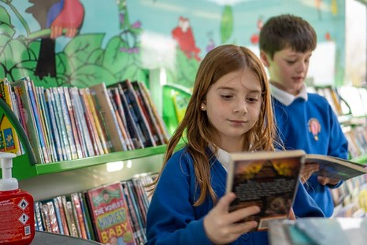 A schoolgirl smiles as she reads a book.