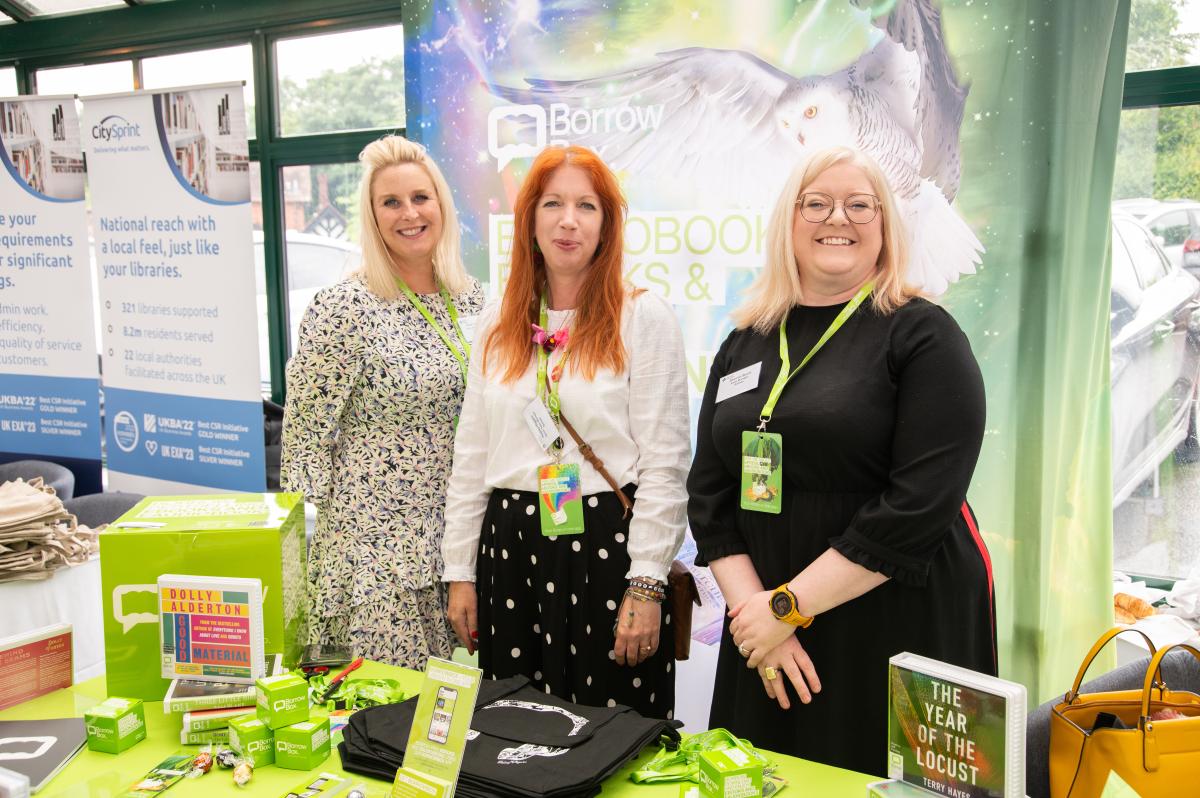 Three people stood at a sponsor's stand