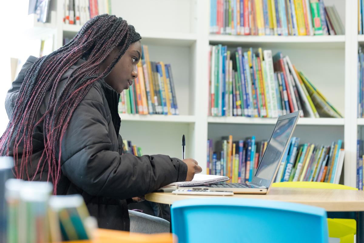 A young girl studies a book in a library.