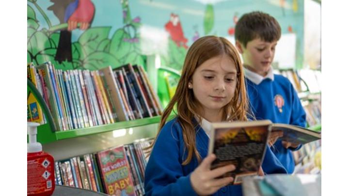 A schoolgirl smiles as she reads a book.