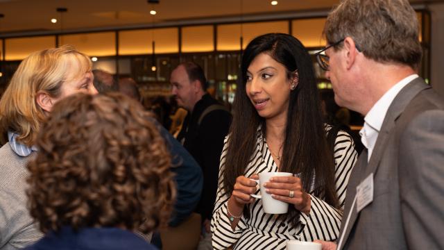 A group of people are engaged in conversation, enjoying a casual networking event over coffee.