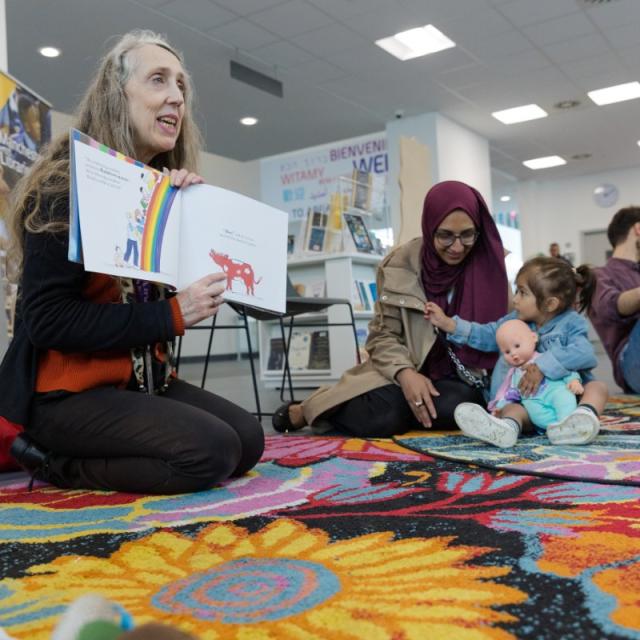 Toddlers reading group - all sitting on floor on rug in a library