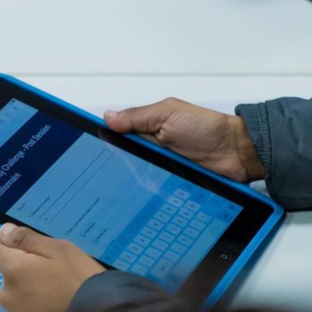 Two hands holding a tablet computer with a form on the screen