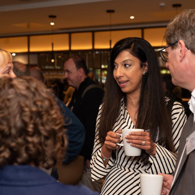 A group of people are engaged in conversation, enjoying a casual networking event over coffee.