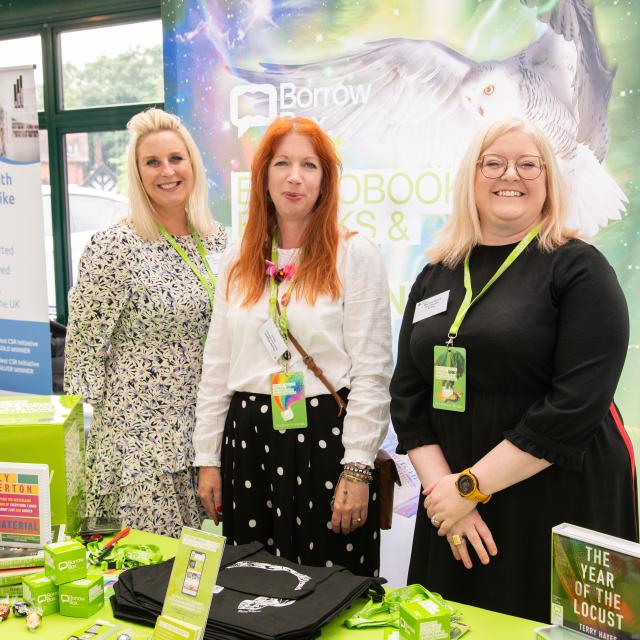 Three people stood at a sponsor's stand