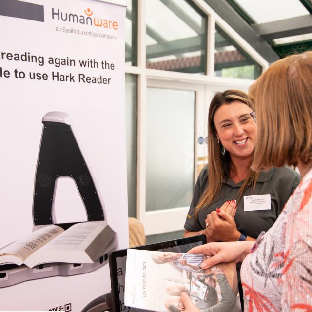 Two people talking in front of a sponsor's stand