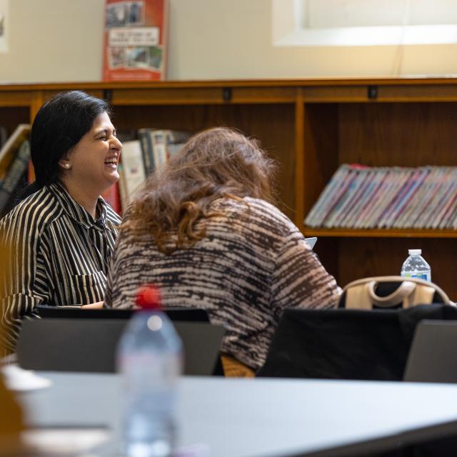 A woman laughts in a library.